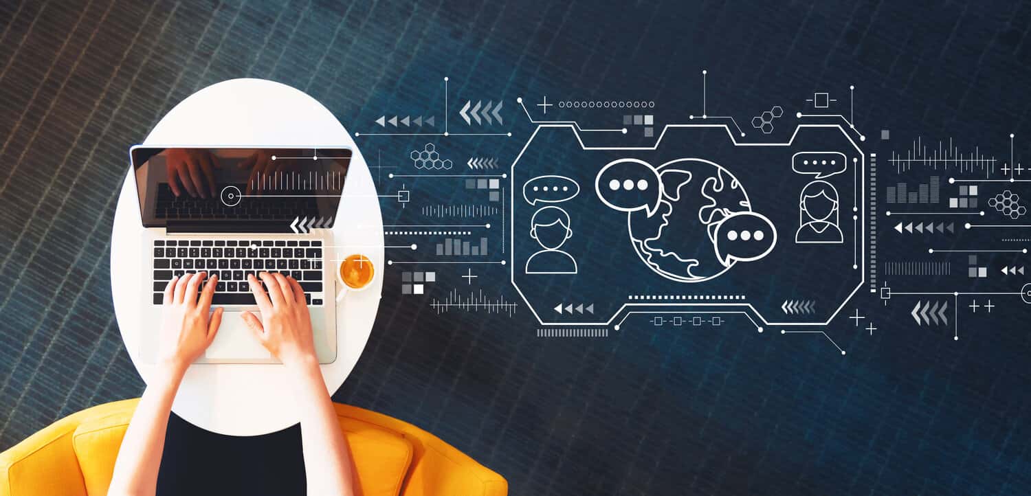 An Image of a person using a laptop while seated with a coffee cup next to them. There is a illustrated overlay of people communicating and engaging from around the world.